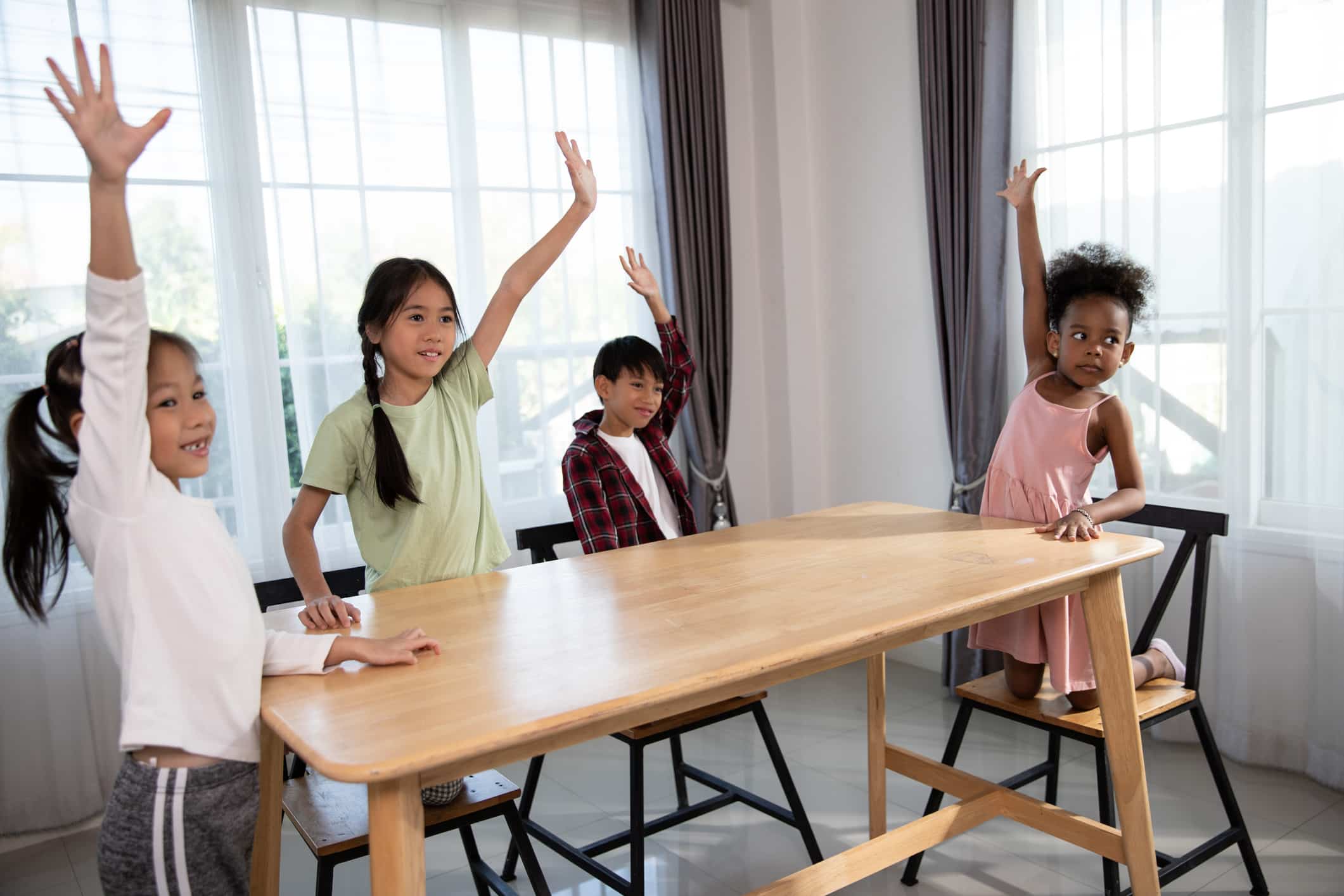 Group of kids raising their hands to answer a question in a classroom