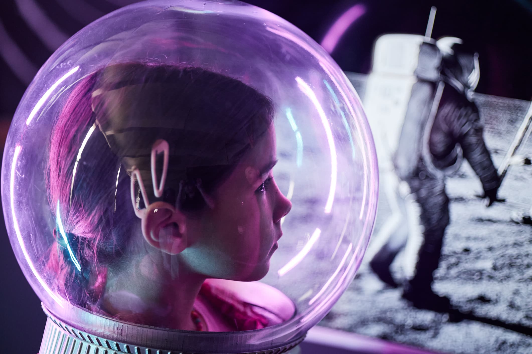 Girl in a space helmet watching an astronaut walk on the Moon