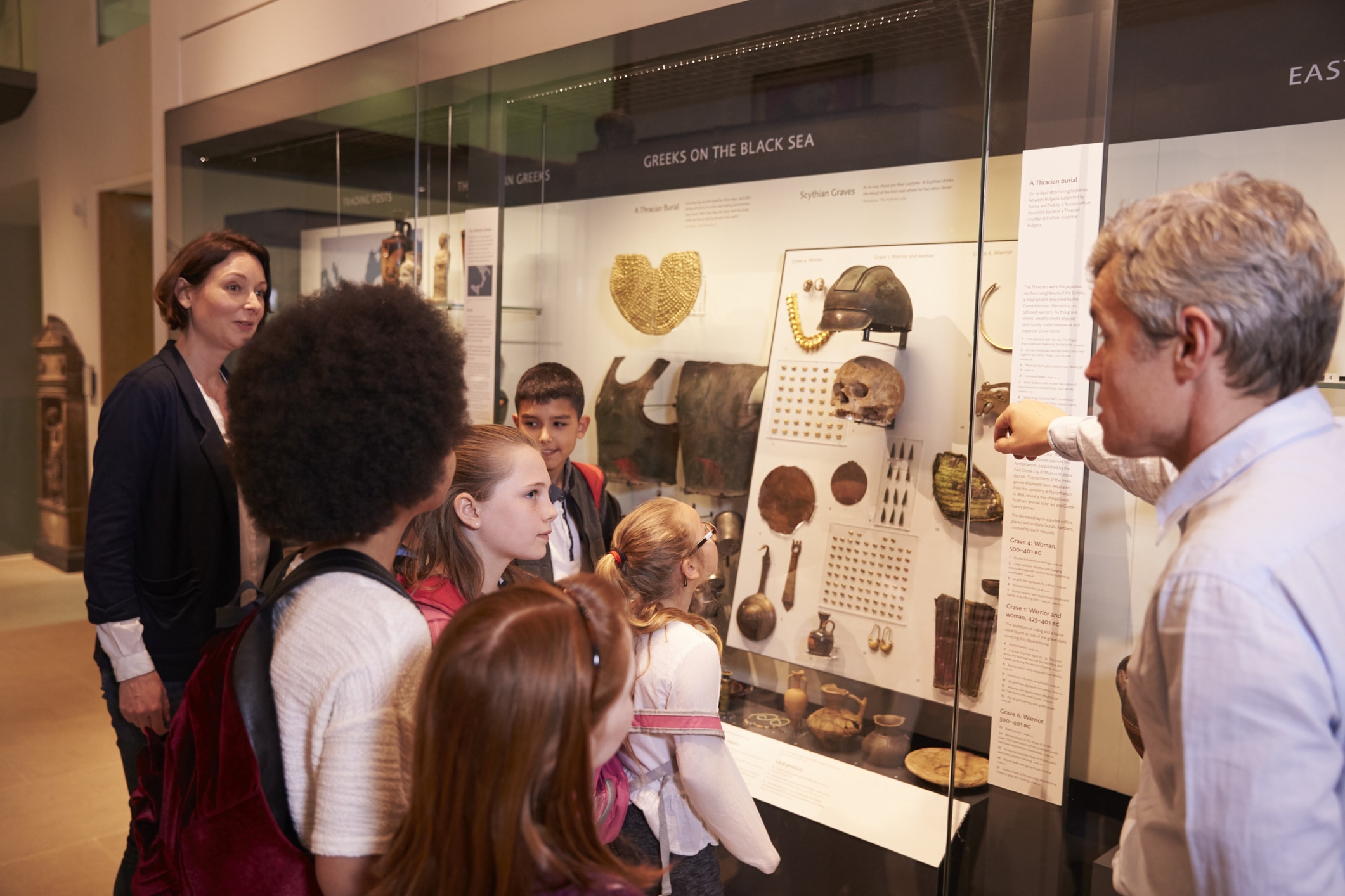 Students looking at ancient Egyptian artifacts in a museum display case on a school trip