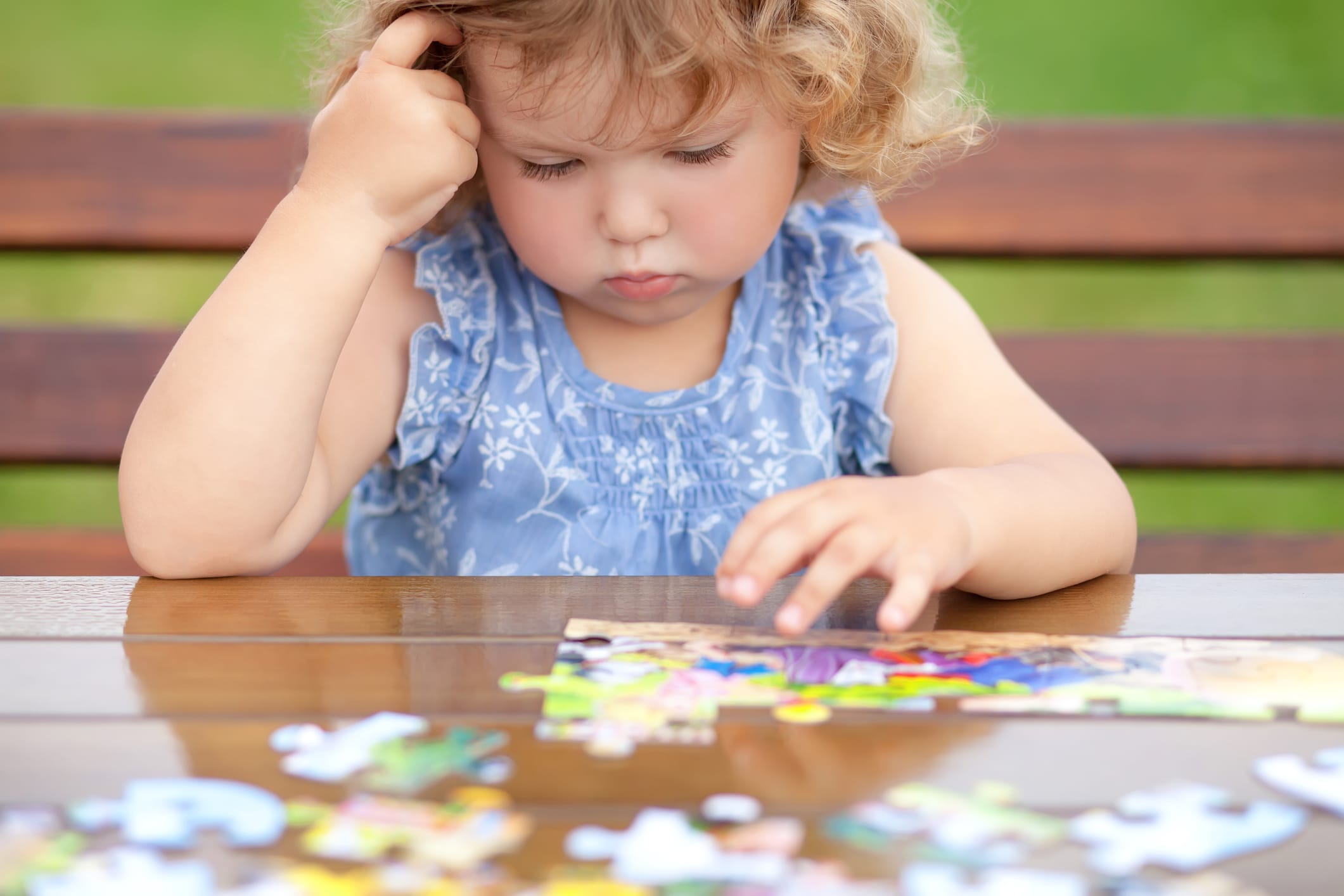 Little girl resting her head on her hand, stumped over a jigsaw puzzle