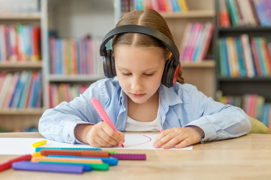 Elementary student wearing headphones while drawing at a desk